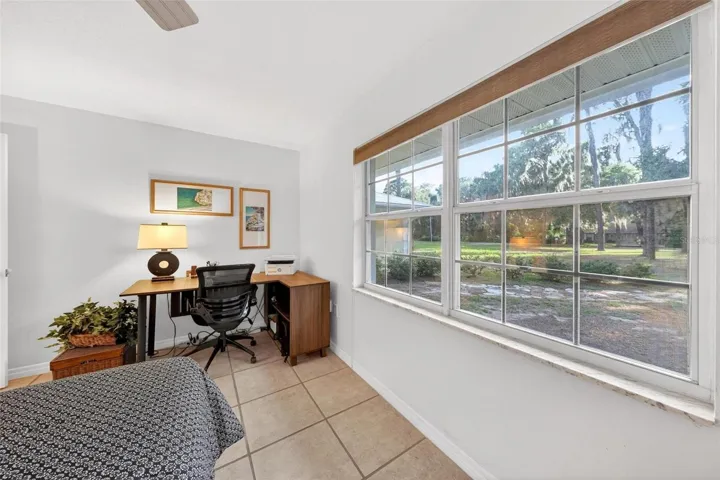 This inviting third bedroom offers a peaceful view of the wooded front landscape, creating a calm and comfortable space for guests, children, or working from home while staying connected to the natural beauty surrounding the property.