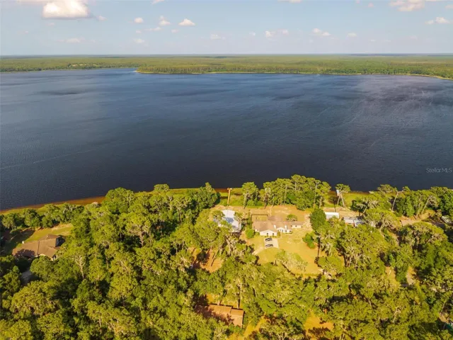 Positioned behind a natural wooded buffer and accessed by a private road, this Lake Dorr retreat offers a rare blend of privacy, serenity, and waterfront beauty. The elevated aerial perspective captures the home’s exceptional setting, where protected natural surroundings meet expansive lake views for a lifestyle that feels both secluded and refined.