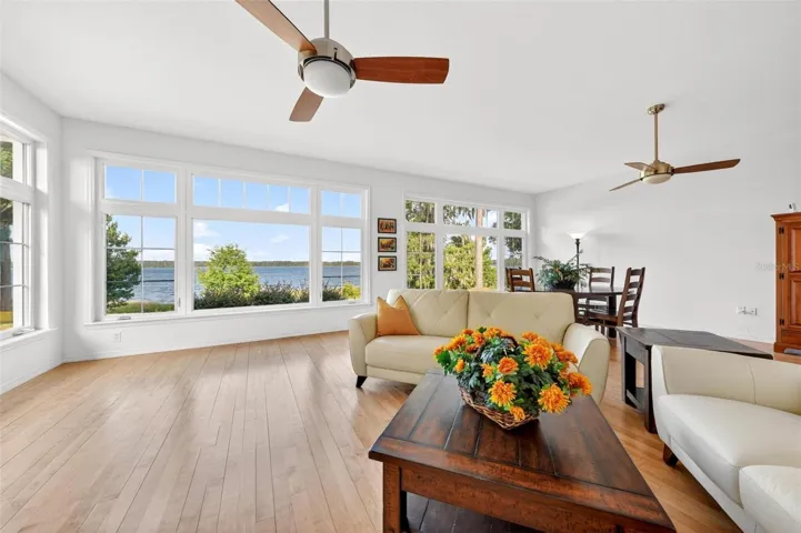 Open and airy gathering space features warm wood flooring, clean neutral finishes, and a seamless connection to the outdoors, creating the perfect setting for relaxing, entertaining, or simply enjoying the beauty of lakefront living from inside the home.