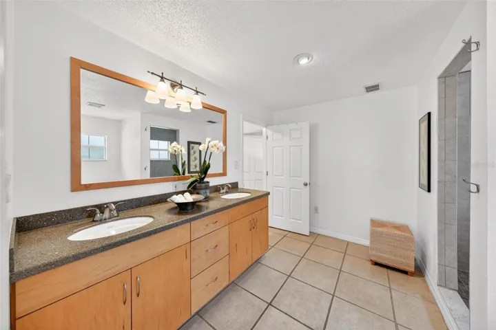 The second primary suite is complemented by a spacious Jack-and-Jill style en-suite bath with dual sinks, abundant storage, and a walk-in tiled shower — ideal for guests, extended family, or anyone who appreciates privacy and convenience.