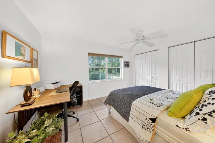 Comfortable third bedroom overlooking the wooded front setting, offering natural light, generous closet space, and flexibility for guests, family, or a home office. The peaceful view toward the mature trees adds to the home’s private retreat feel, making this room both practical and inviting.