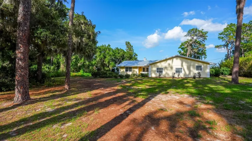 Welcome to a peaceful arrival beneath towering trees, where Old Florida charm, privacy, and natural beauty set the tone for this Lake Dorr retreat.