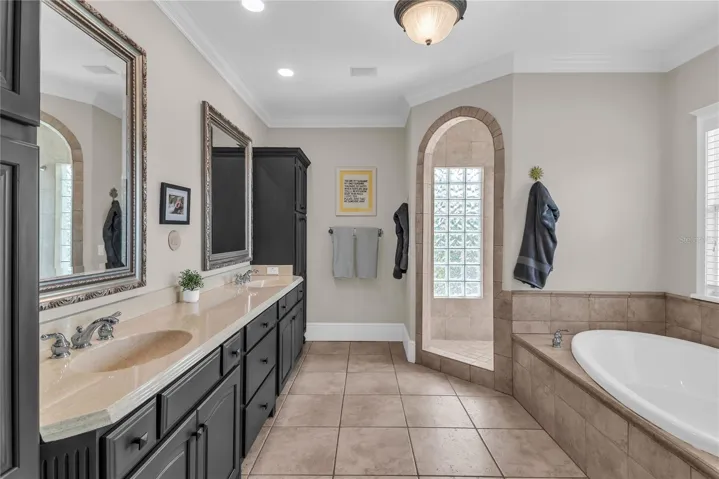 Spacious primary bathroom with dual sinks, toilet closet, soak tub and large walk-in shower
