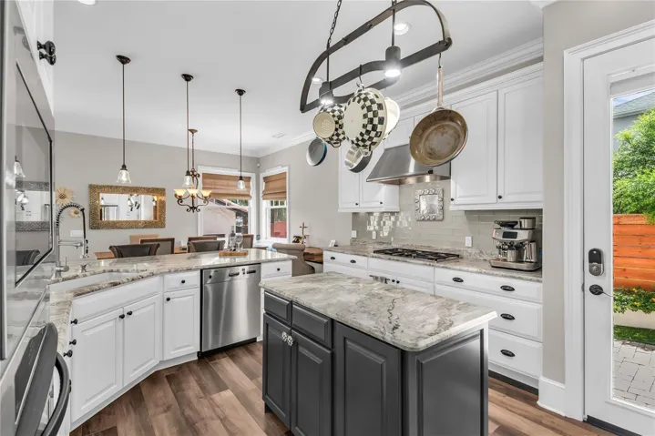 Beautiful kitchen with bar seating, gas cooktop and hood, island and stainless steel appliances