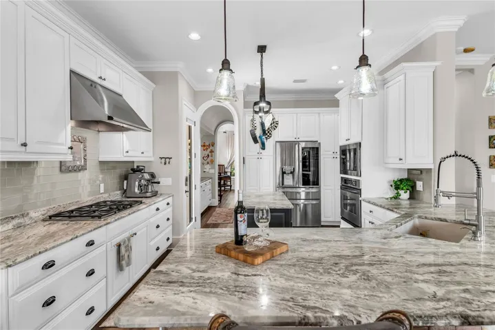 Beautiful kitchen with bar seating, gas cooktop and hood, island and stainless steel appliances