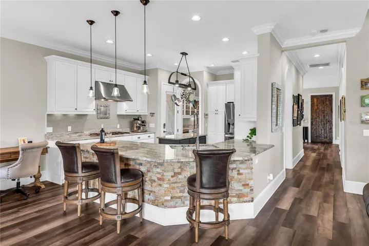 Beautiful kitchen with bar seating, gas cooktop and hood, island and stainless steel appliances