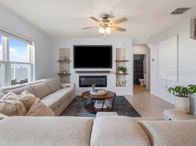 View of living room from kitchen. Custom entertainment wall with built ins and fireplace added after new build