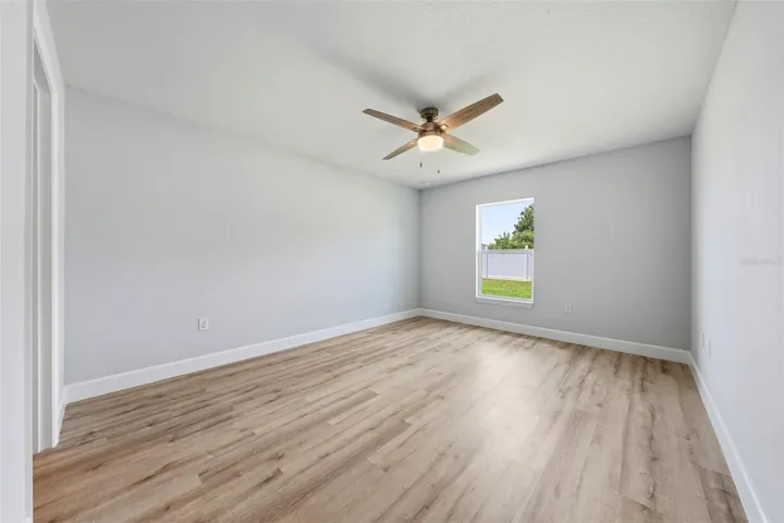 Spacious primary bedroom with luxury vinyl plank flooring and ceiling fan