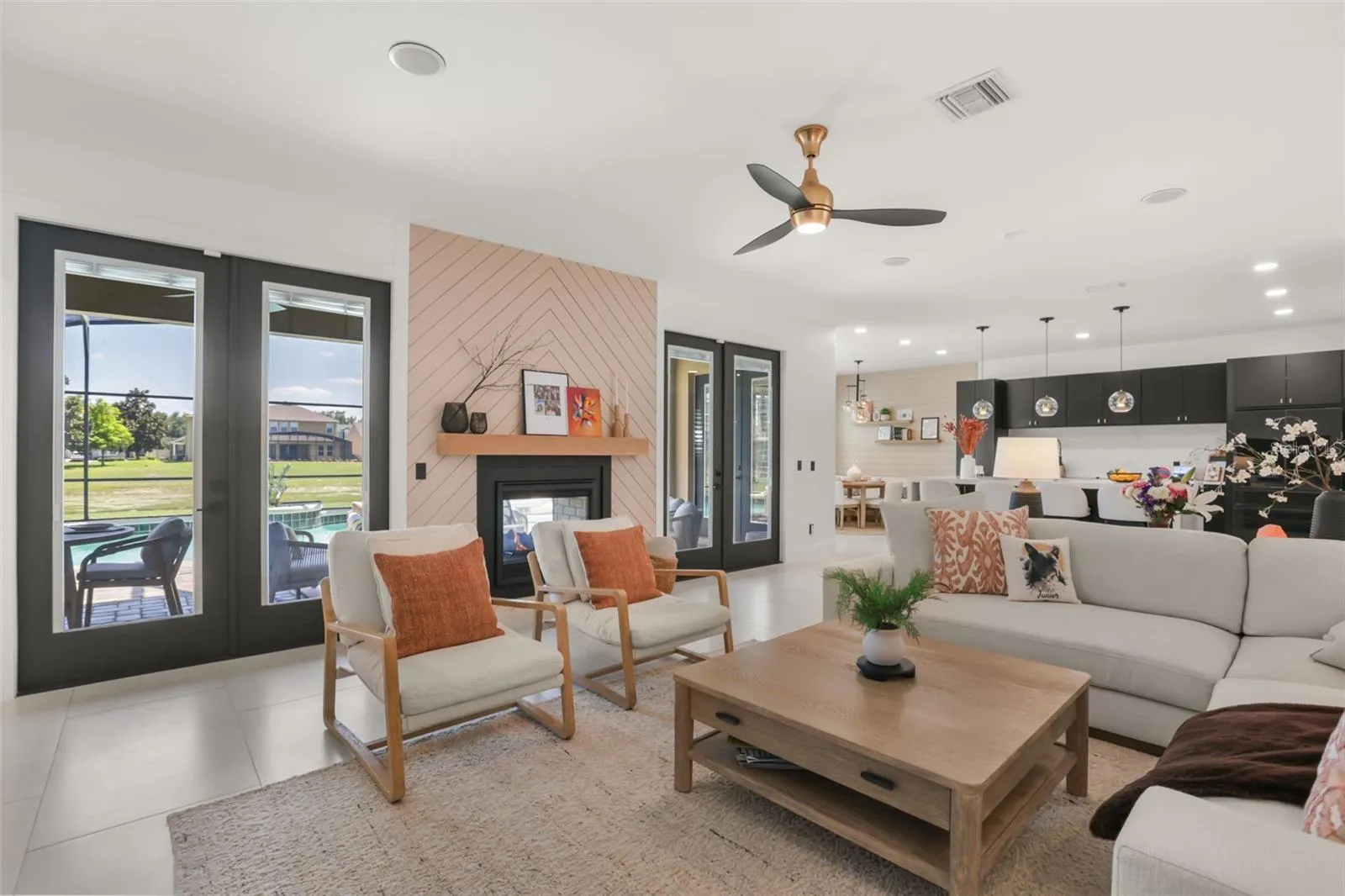 The family room includes a sleek fireplace accent wall, multiple glass doors, and views toward the outdoor living and pool area.