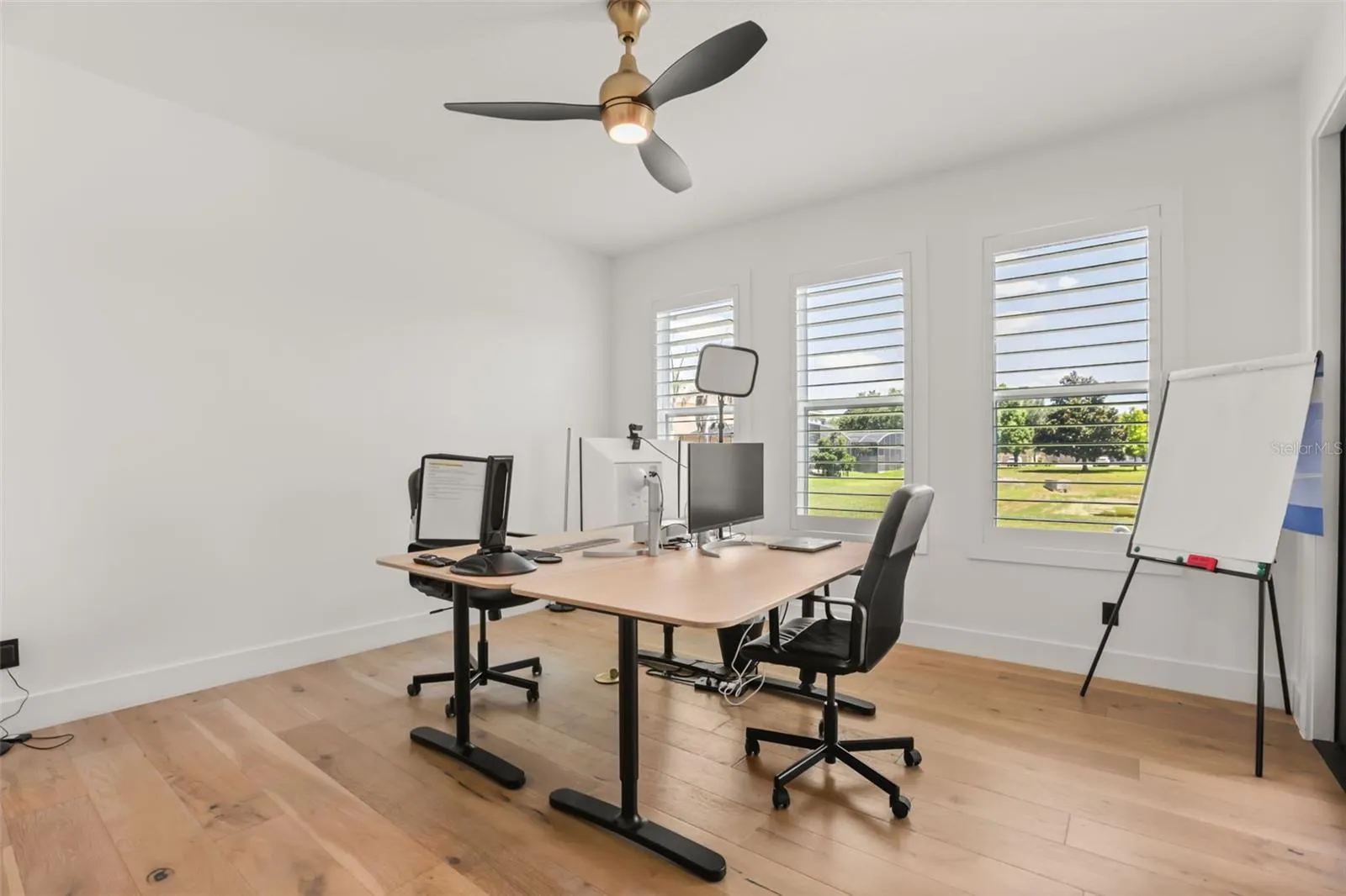 A dedicated office space features wood flooring, plantation shutters, and room for multiple workstations or flexible use.