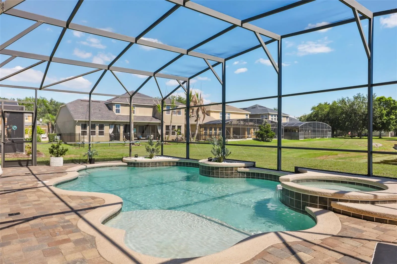 This outdoor retreat includes a spacious paver deck, integrated spa, and screened enclosure designed for comfortable relaxation.