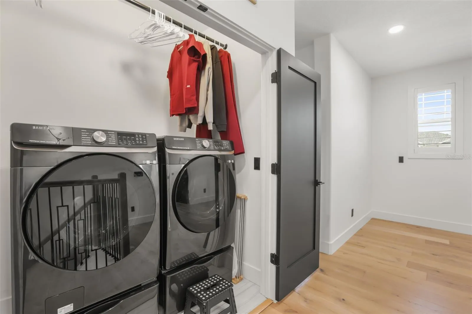 The upstairs laundry space includes front-load appliances, hanging storage, and convenient placement near the upper-level bedrooms.