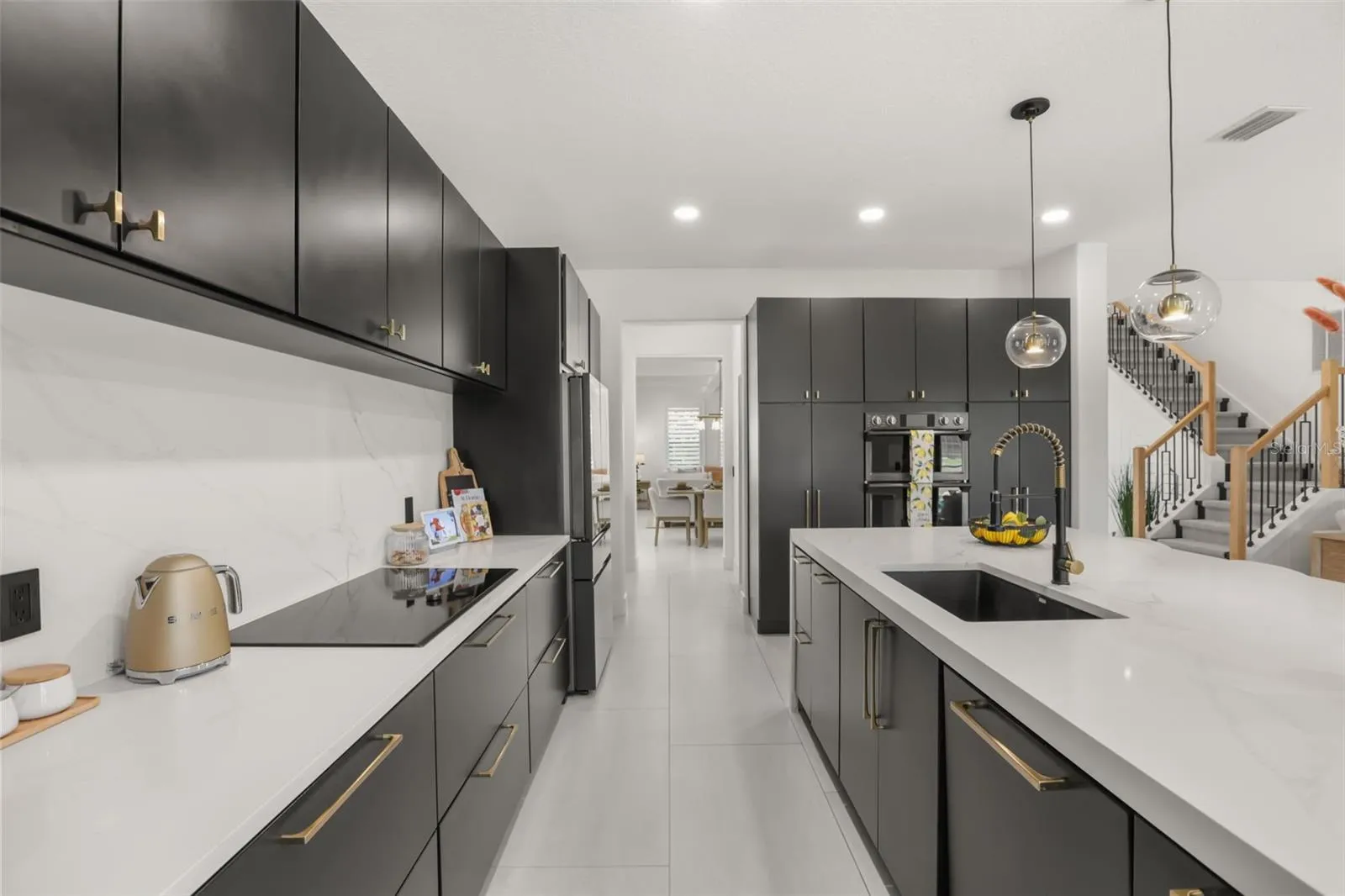 The kitchen offers expansive counter space, an integrated cooktop, a deep island sink, and streamlined cabinetry for a functional modern layout.