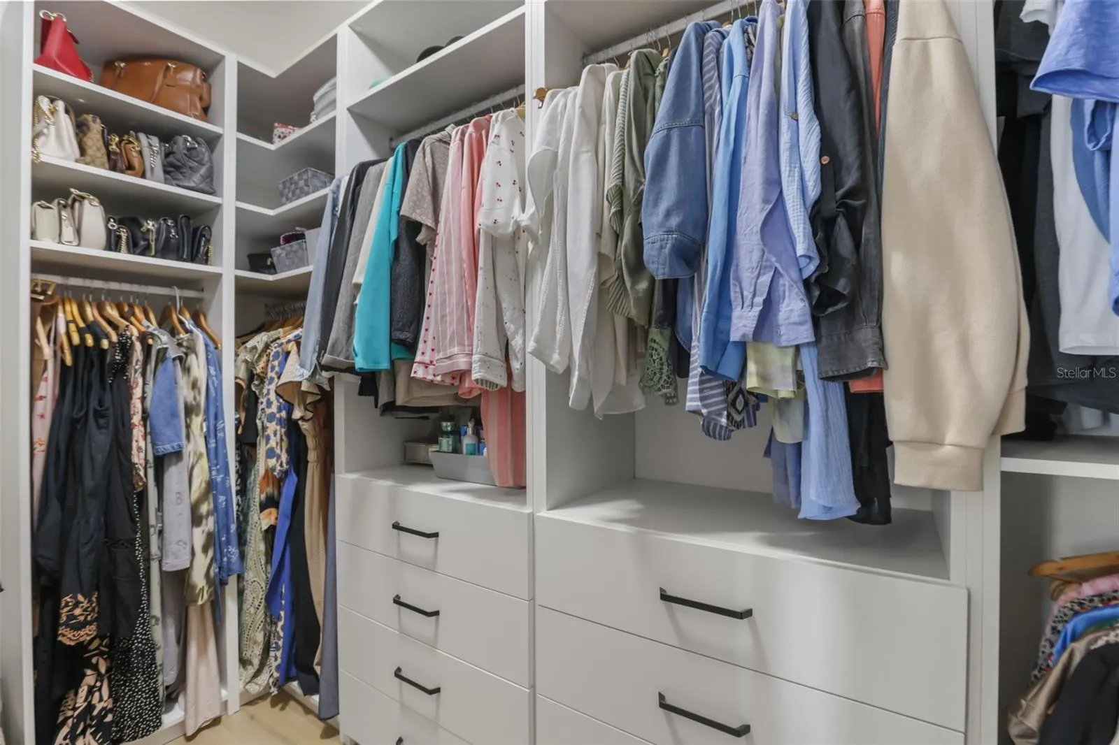 This custom closet includes drawer banks, open shelving, and multiple hanging sections for organized, accessible storage.