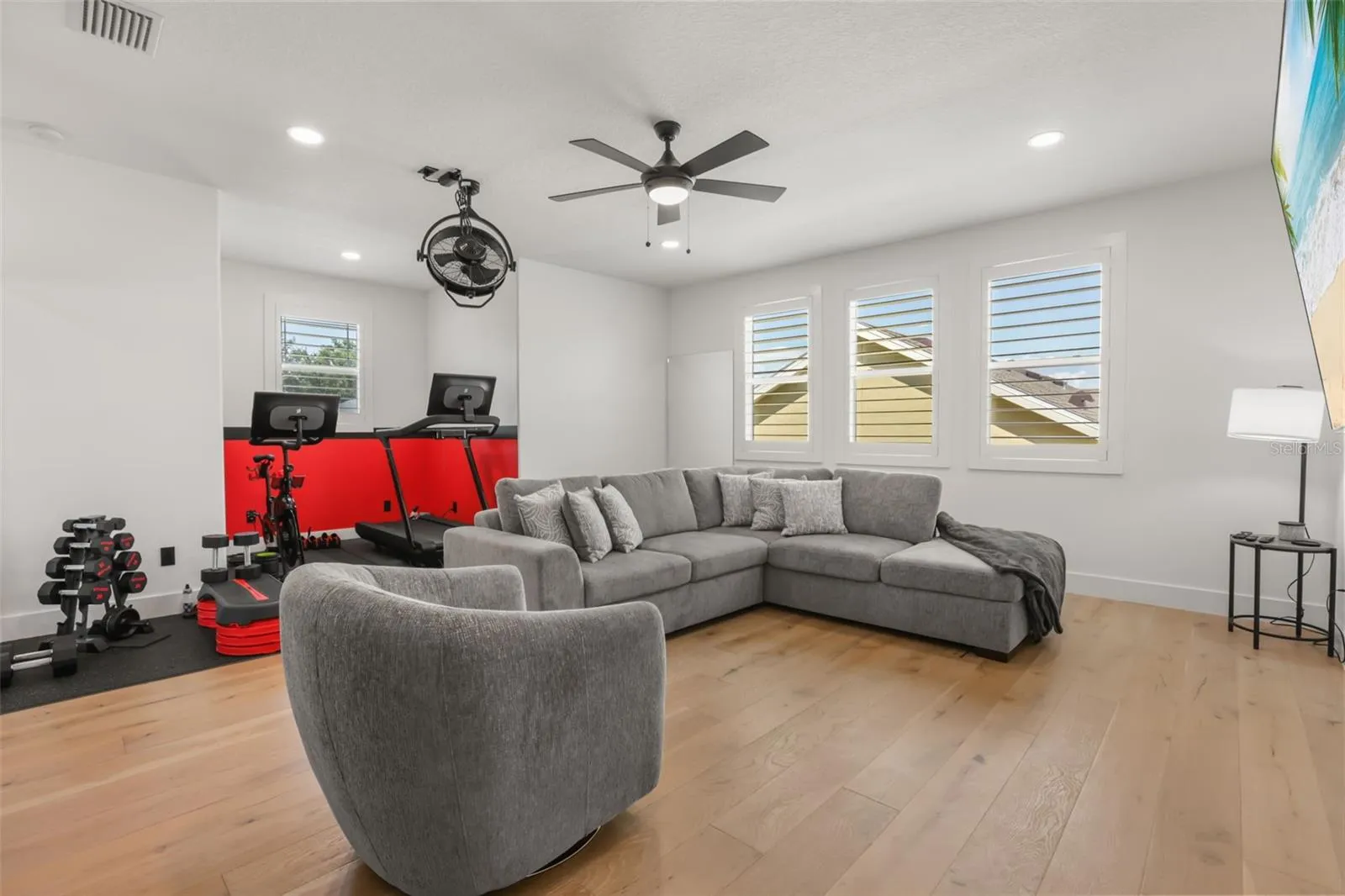 This spacious bonus room combines a lounge area with a dedicated fitness zone, offering flexibility for recreation, workouts, or media use.