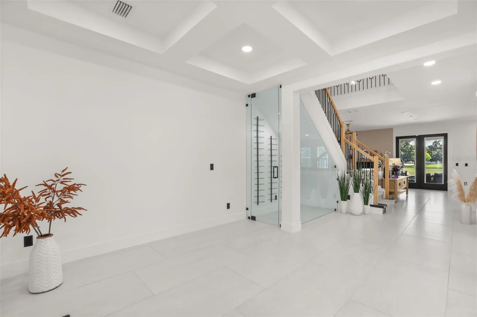 The main hallway showcases sleek architectural lines, a statement staircase, and a glass-enclosed wine display for a refined design touch.