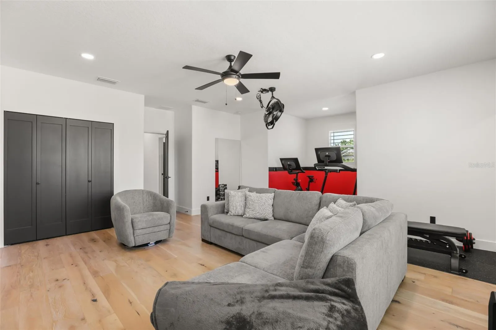 This upstairs flex area offers wood flooring, generous seating, closet storage, and an integrated fitness zone.