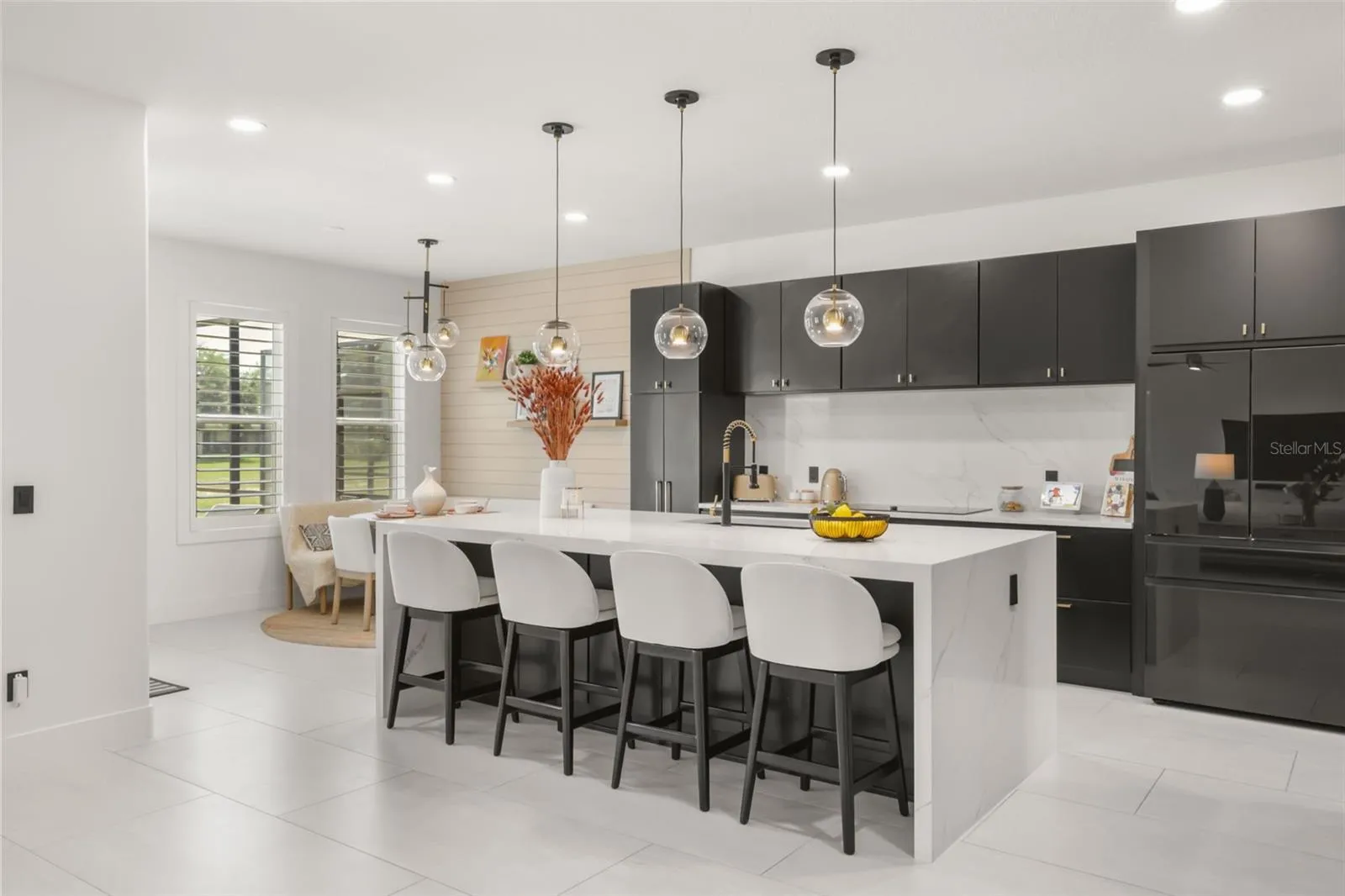 A dramatic waterfall island anchors the kitchen, paired with dark cabinetry, globe pendant lighting, and bar seating for everyday dining or entertaining.