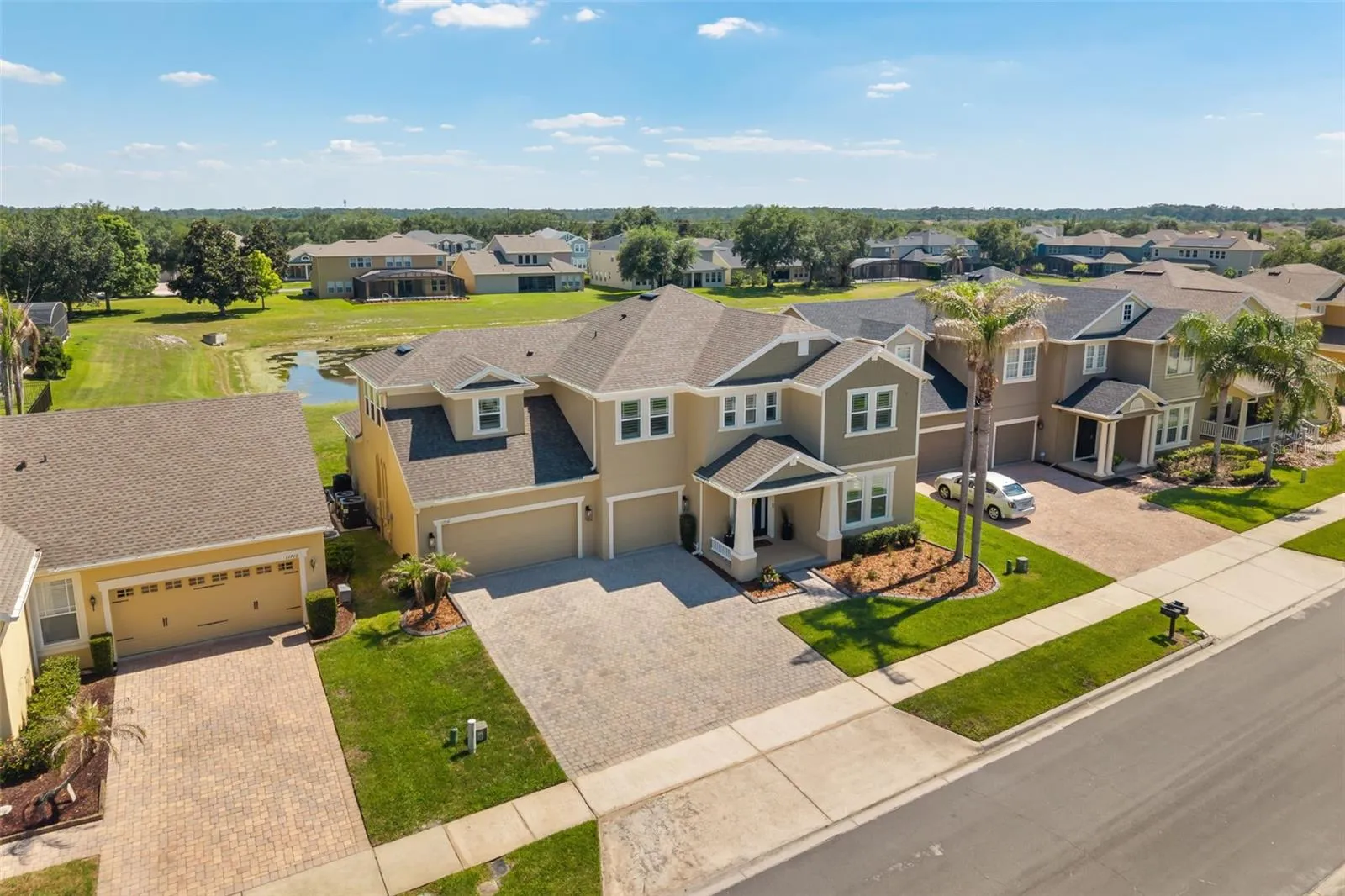 This elevated view highlights the home’s curb appeal, spacious driveway, and neighborhood setting with green space and water views nearby.