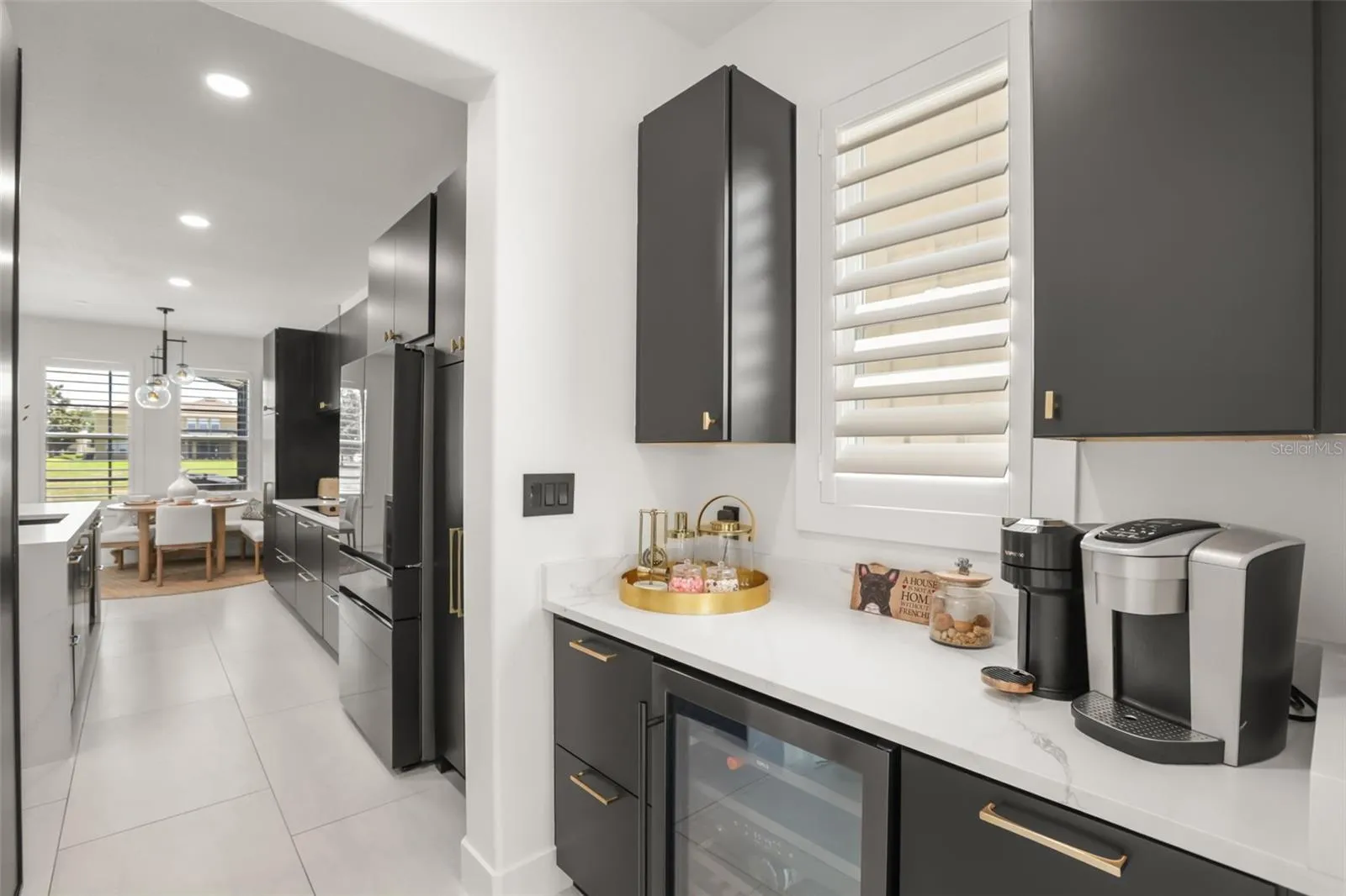 A dedicated beverage and coffee station features marble-look counters, dark cabinetry, a wine fridge, and additional prep or storage space.