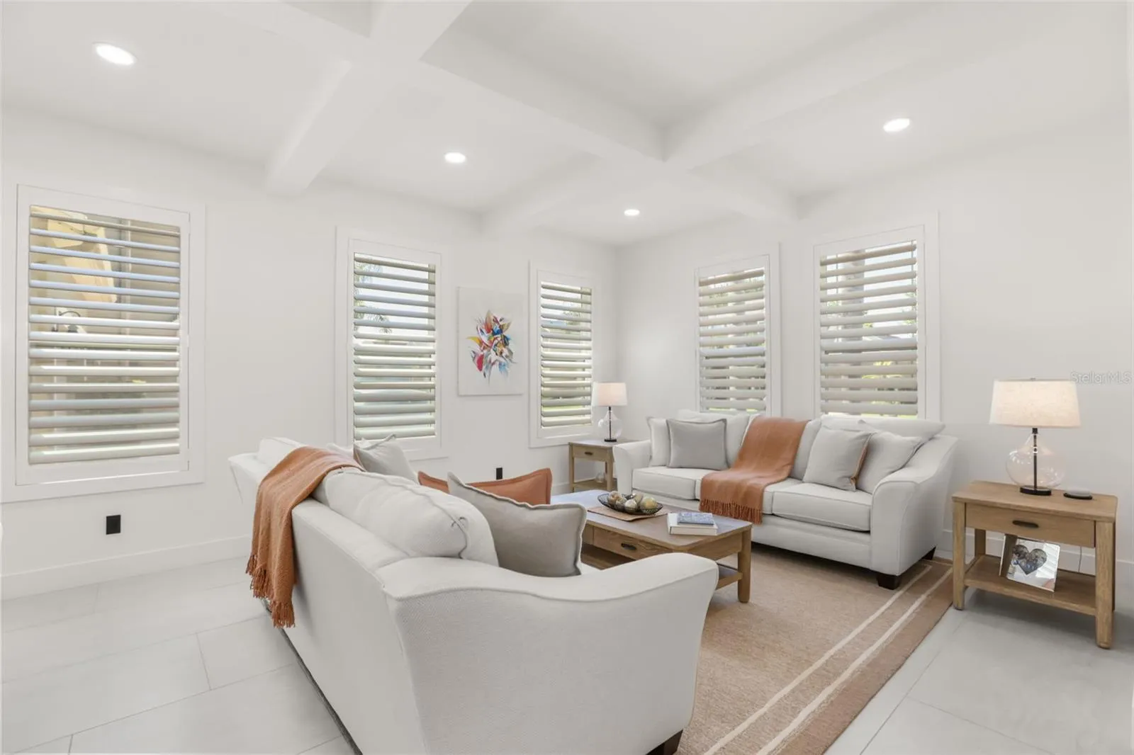 This inviting sitting area features plantation shutters, soft neutral finishes, and abundant natural light for a comfortable gathering space.