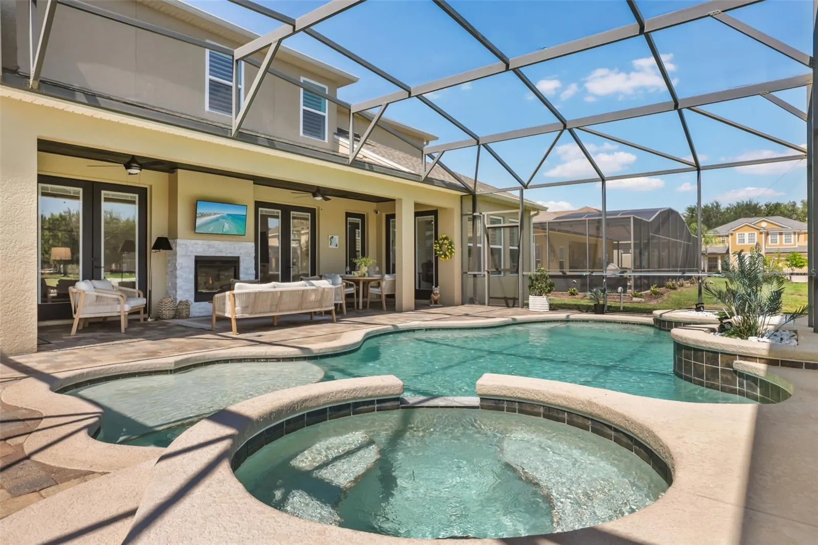 A screened outdoor retreat features a pool, raised spa, paver deck, and covered lanai for comfortable outdoor living.
