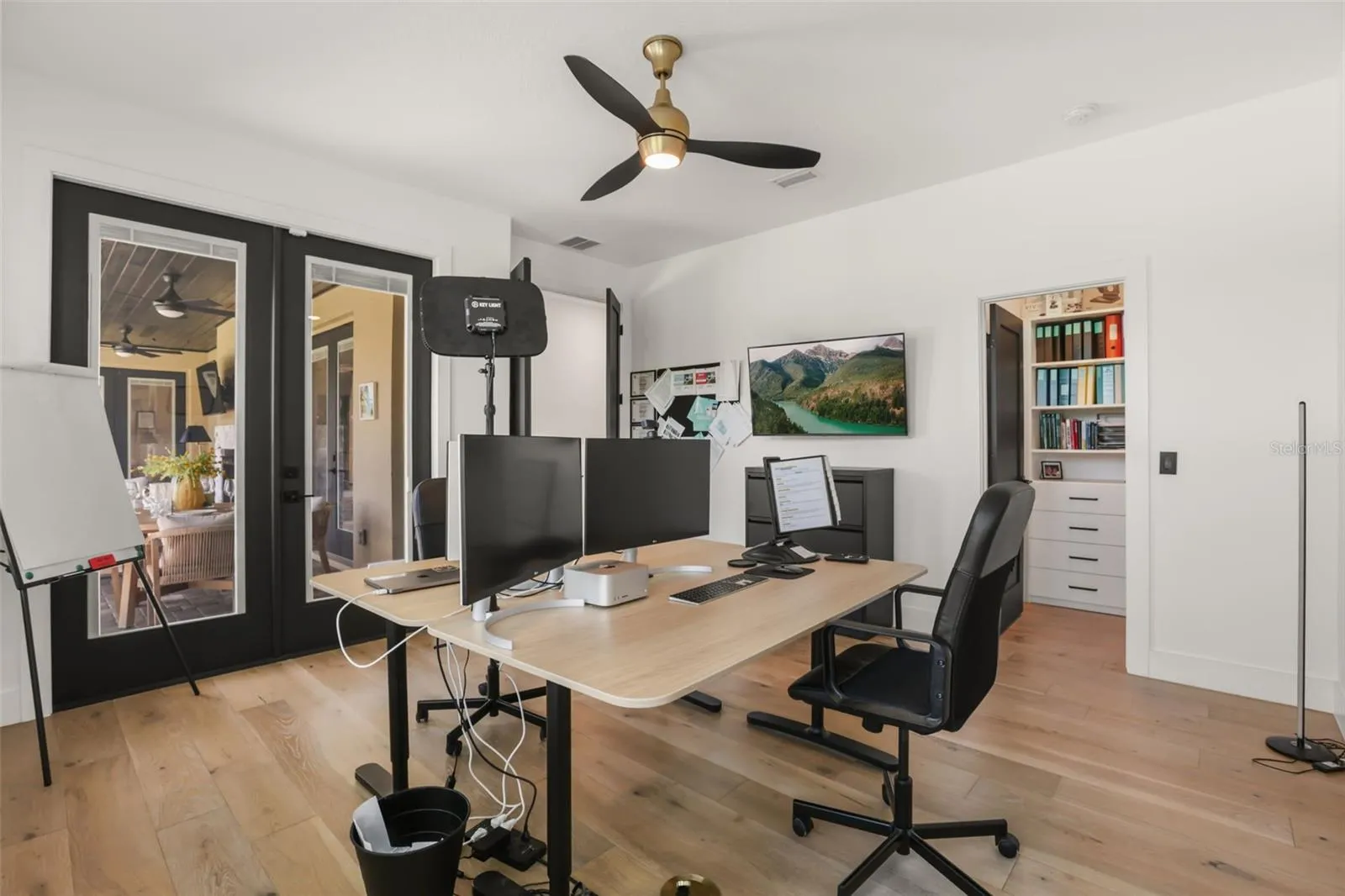 French doors connect the office to the outdoor living area, while built-in storage nearby adds convenience and function.