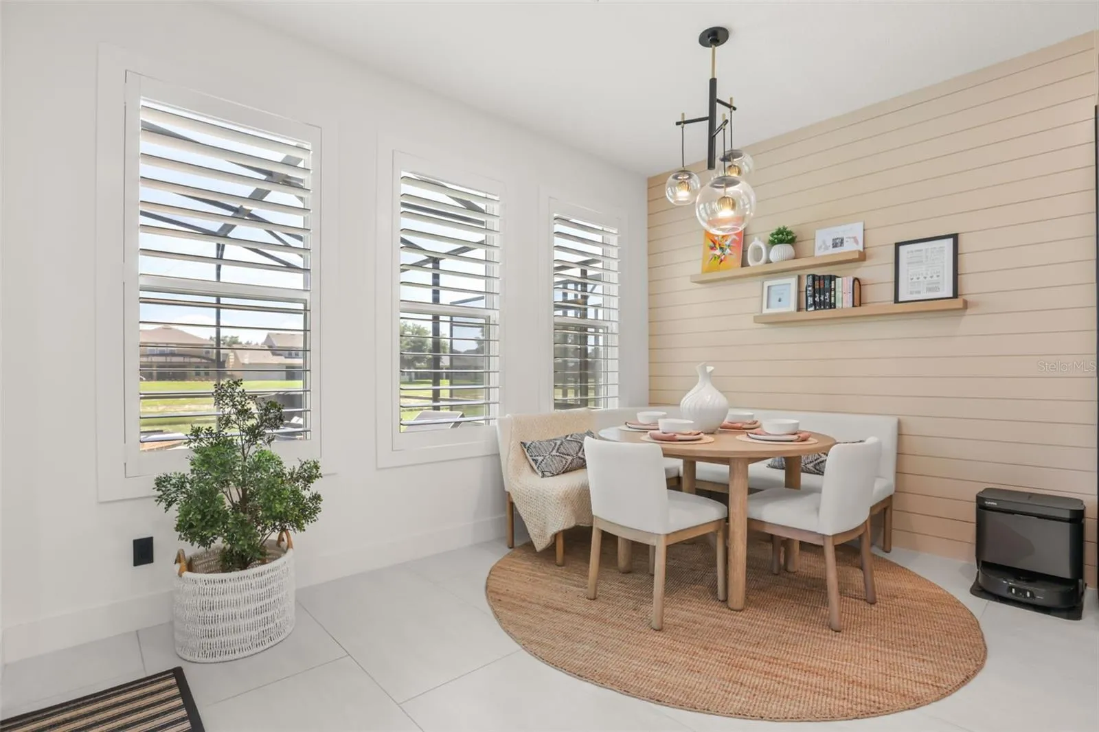 The breakfast nook features a shiplap accent wall, built-in shelves, modern lighting, and large windows overlooking the outdoor area.