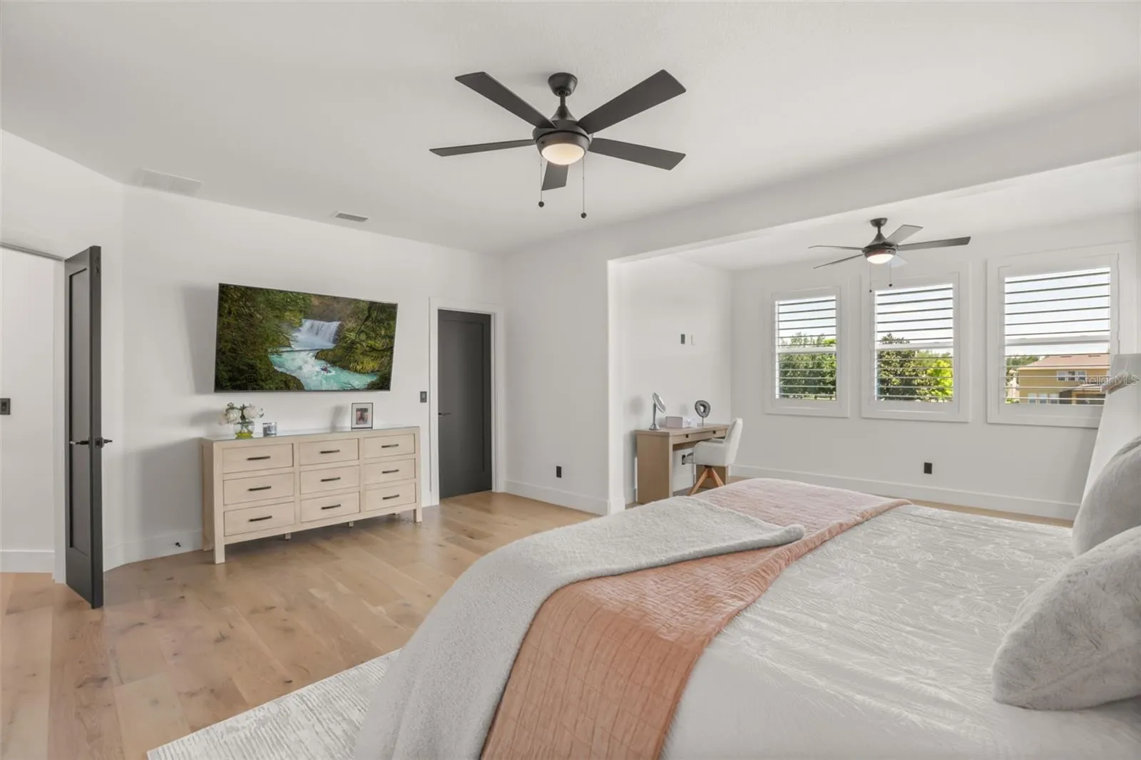 A defined sitting or workspace area adds flexibility to the primary suite, framed by natural light and plantation shutters.
