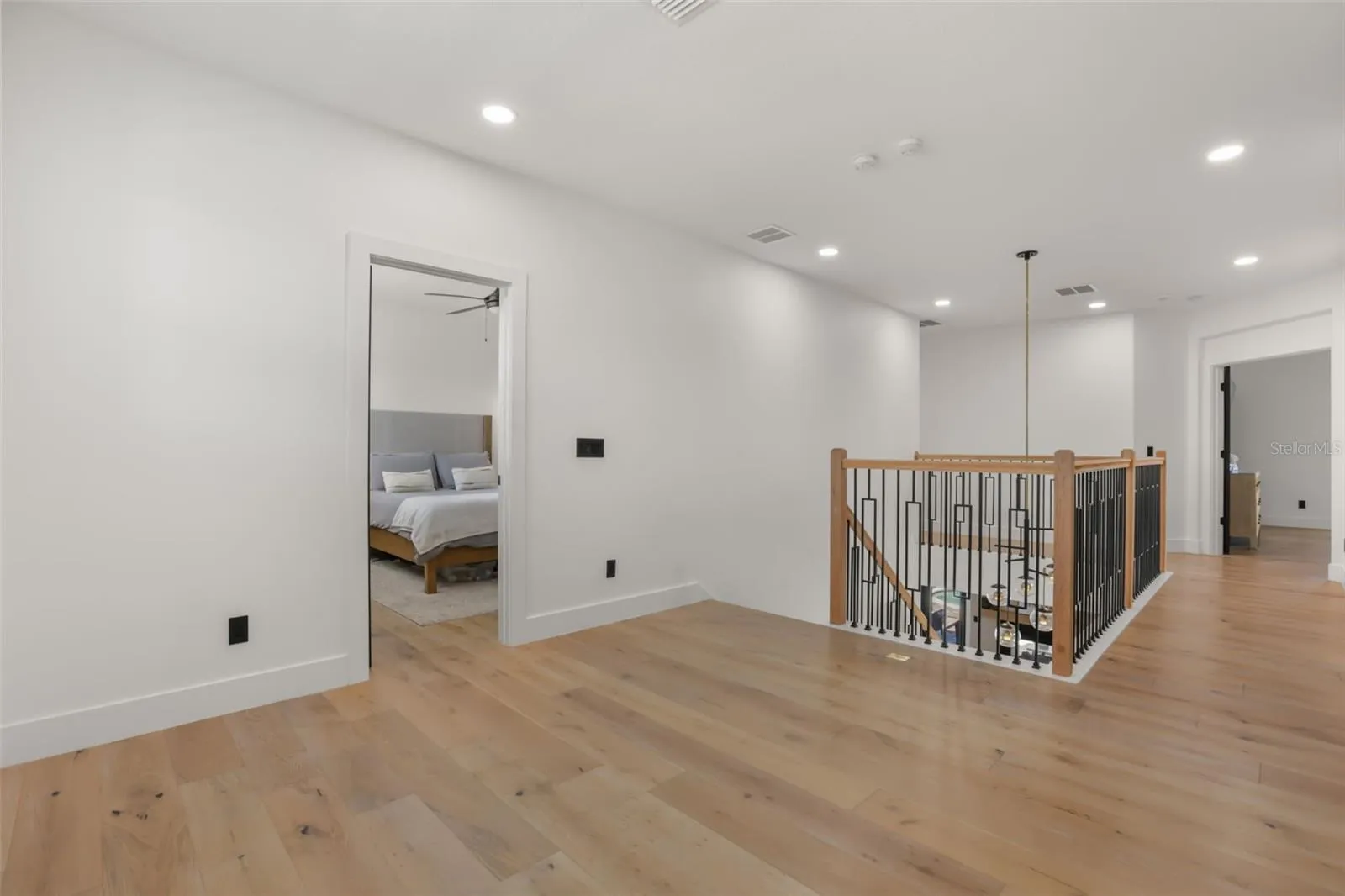 A bright upstairs hallway offers open sightlines over the staircase and connects the home’s private upper-level spaces.