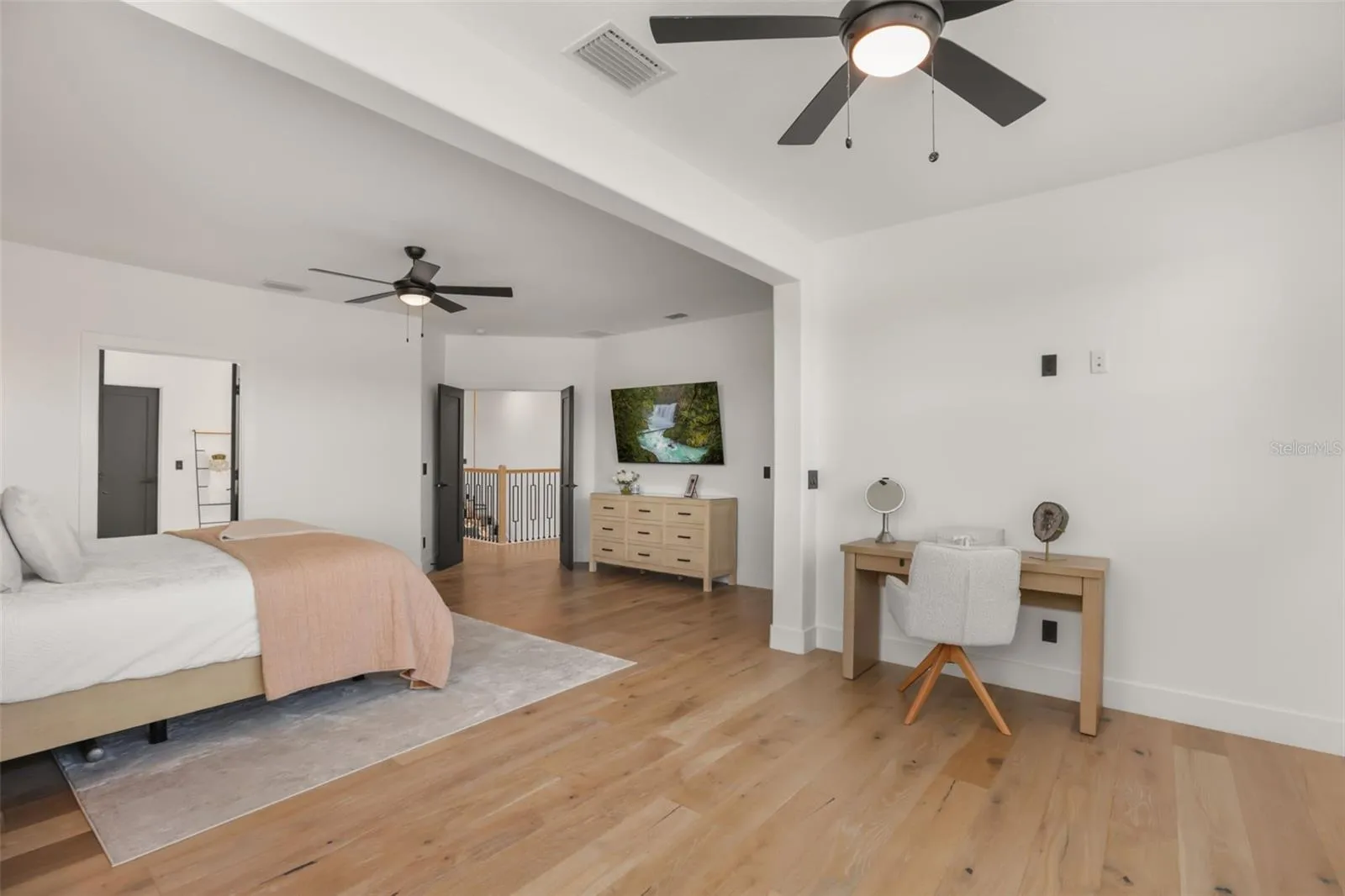 This wide bedroom view highlights the generous layout, plantation shutters, and dedicated desk or dressing nook.
