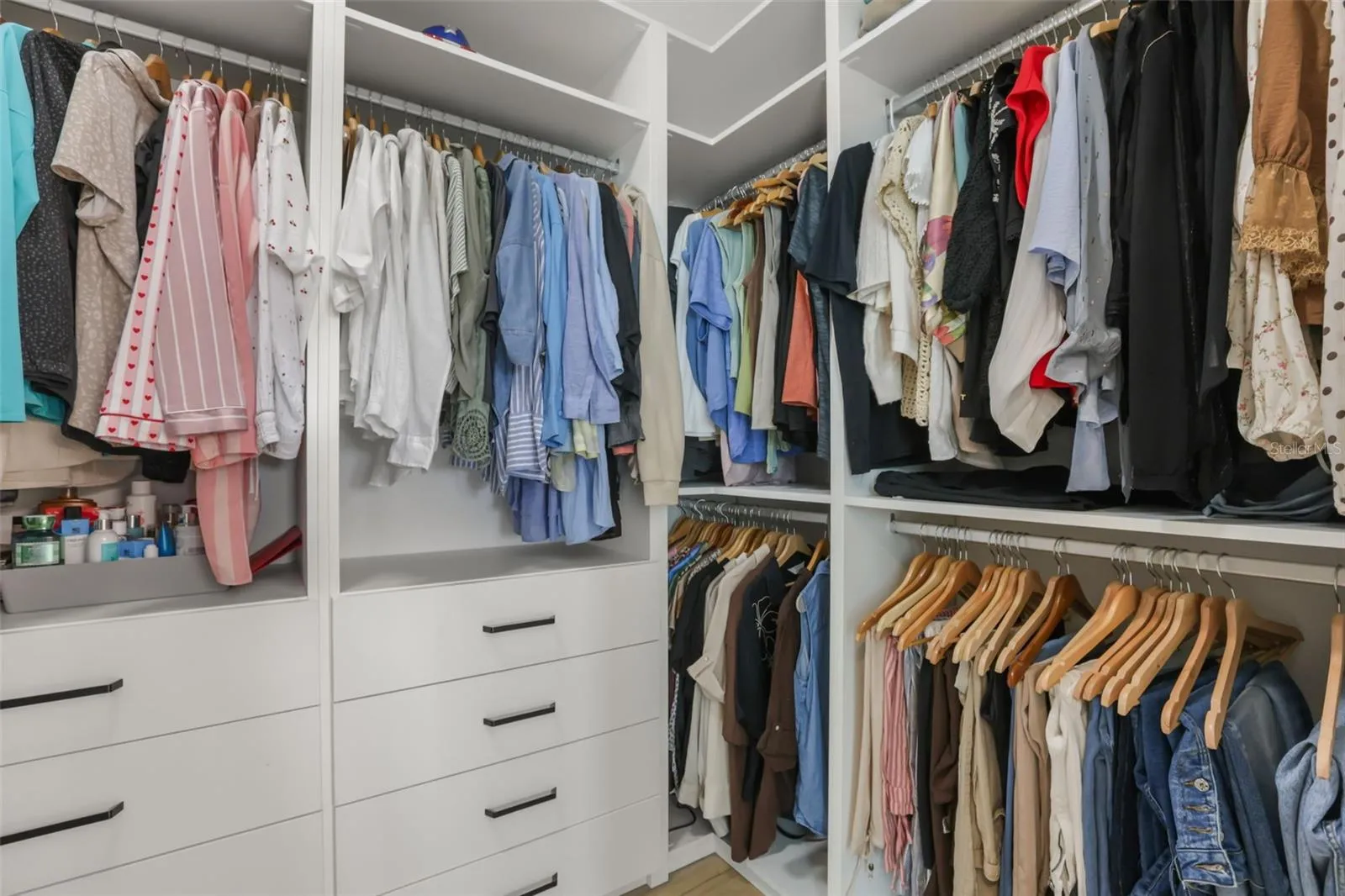 A well-planned closet layout features floor-to-ceiling built-ins, varied hanging areas, and integrated drawers for added convenience.