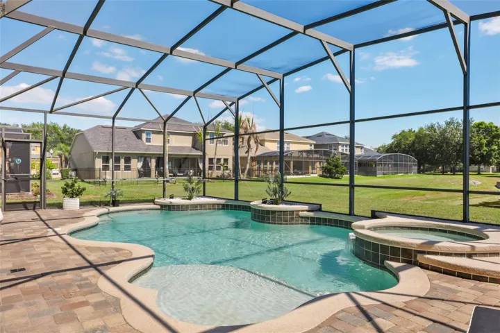 This outdoor retreat includes a spacious paver deck, integrated spa, and screened enclosure designed for comfortable relaxation.