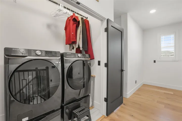 The upstairs laundry space includes front-load appliances, hanging storage, and convenient placement near the upper-level bedrooms.