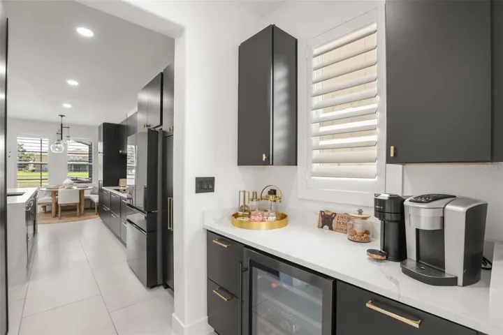 A dedicated beverage and coffee station features marble-look counters, dark cabinetry, a wine fridge, and additional prep or storage space.