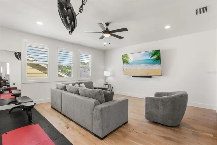 A comfortable sectional, wall-mounted TV, and nearby exercise area make this bonus room ideal for both relaxing and active use.