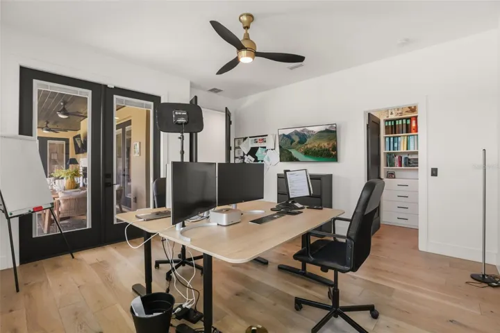 French doors connect the office to the outdoor living area, while built-in storage nearby adds convenience and function.