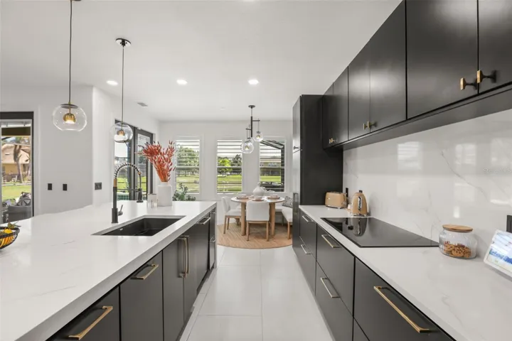 A bright kitchen corridor leads toward the breakfast nook, with plantation shutters, pendant lighting, and a spacious island enhancing the layout.