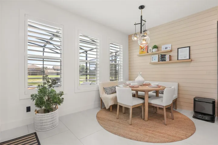 The breakfast nook features a shiplap accent wall, built-in shelves, modern lighting, and large windows overlooking the outdoor area.