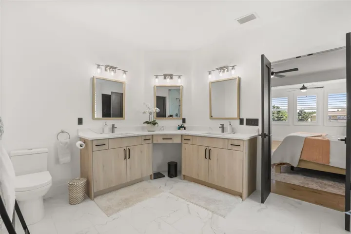 A spacious vanity layout with multiple sinks, light wood cabinetry, and framed mirrors offers both style and everyday function.