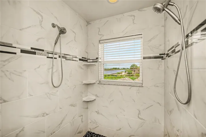 Spa-Like Roman Shower with Dual Showerheads and a Window Framing Serene Water Views.