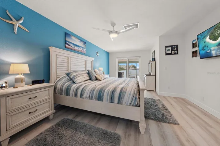 Primary bedroom featuring a wall-mounted TV, sliding glass doors leading to the patio, beautiful sunrise views, and a dedicated makeup vanity area.