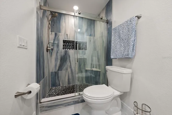 Custom-built shower featuring stunning tile work, vibrant colors, and a convenient corner bench.
