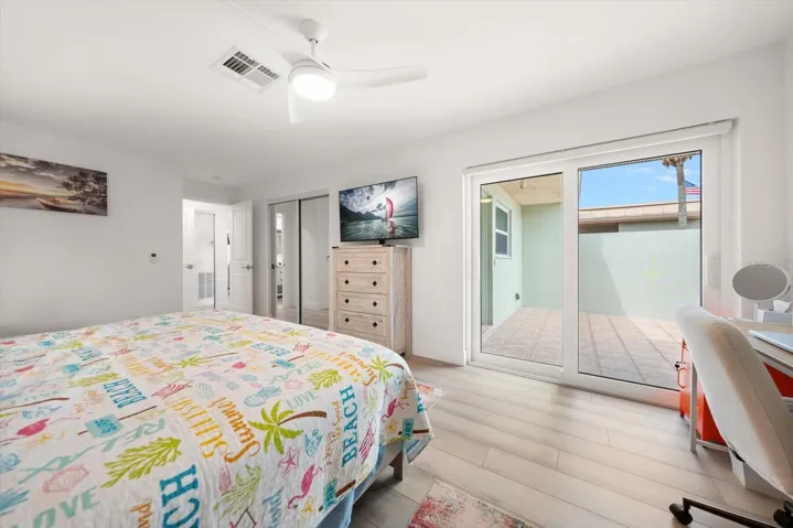 Spacious and bright guest bedroom featuring newly installed hurricane-rated sliding glass doors that provide direct access to the front patio.