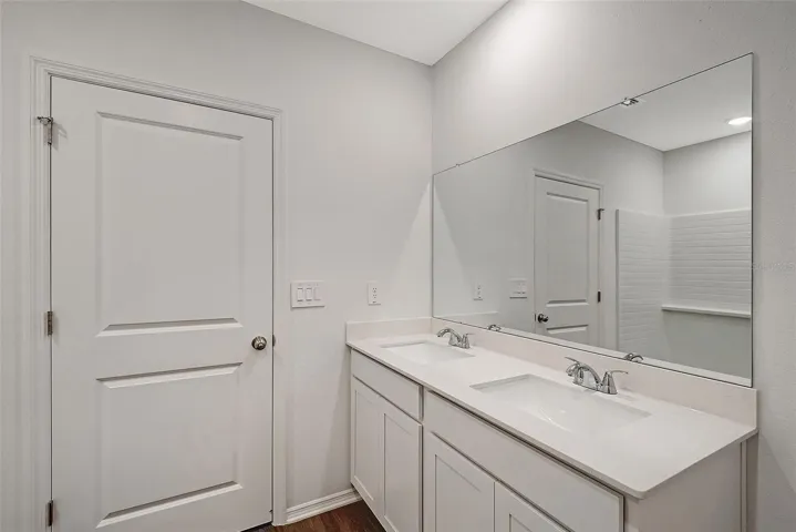 Primary bathroom featuring dual sinks, ample storage, and a clean, modern design.