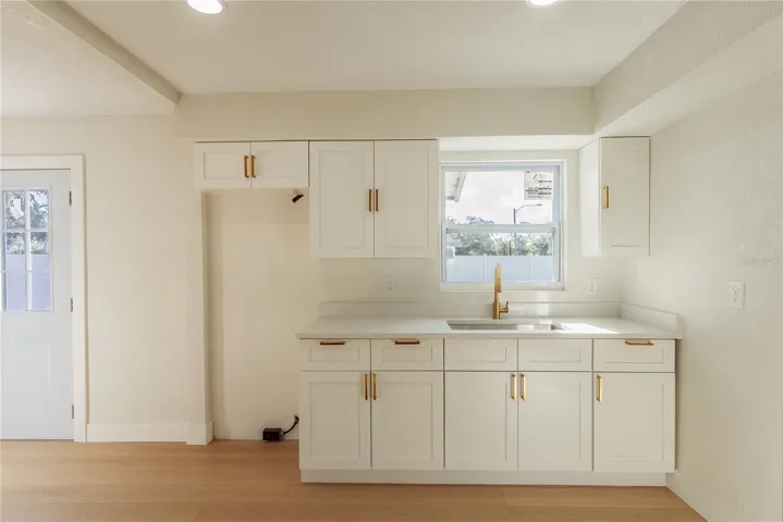 The brand new kitchen features crisp white shaker cabinetry, gleaming gold hardware, quartz countertops, and a deep undermount sink with a gold faucet. Recessed lighting and a sunny window complete the space. An appliance package including refrigerator, oven, range, and microwave will be installed prior to closing.