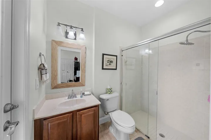 Full bathroom with glass-enclosed shower and vanity storage.