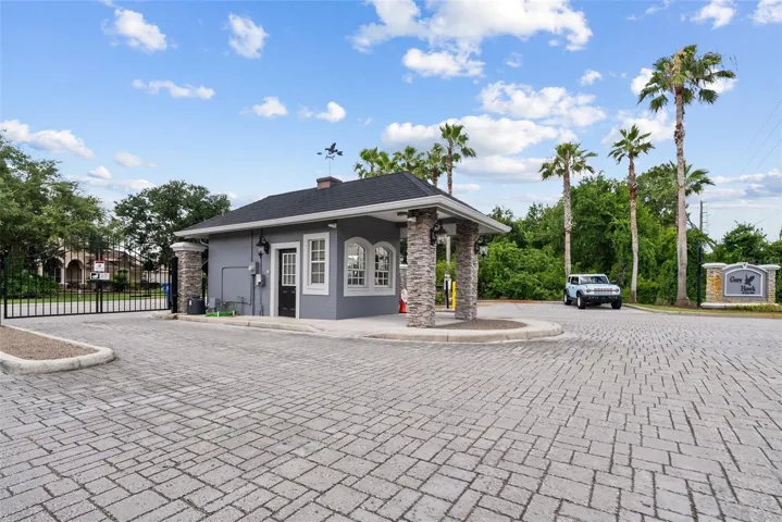 Guard-gated community entrance with pavered drive and secure access.