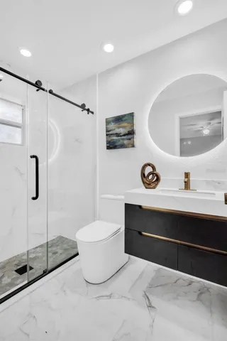 Gorgeous primary suite en-suite bath remodel with walk-in glass enclosed shower, new vanity, commode, tile flooring, and lighting~