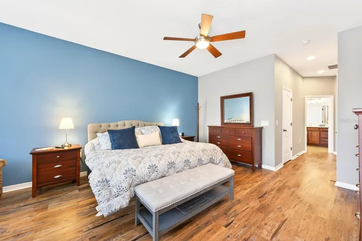 The generous Primary Suite serves as a luxurious retreat, featuring luxury vinyl plank flooring, a sitting area overlooking the pool, PRIVATE ACCESS TO THE LANAI, dual closets—including a walk-in closet—and a SPACIOUS EN SUITE BATH.